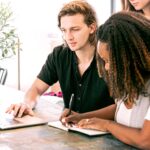 man working on laptop while woman takes notes