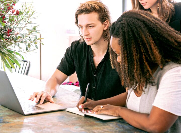 man working on laptop while woman takes notes